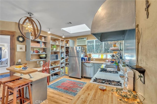 kitchen featuring visible vents, light wood-style flooring, a sink, appliances with stainless steel finishes, and a skylight