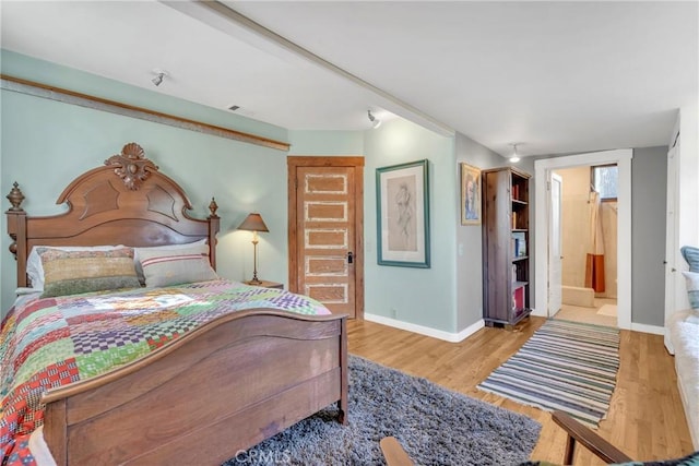 bedroom with ensuite bathroom, baseboards, and wood finished floors