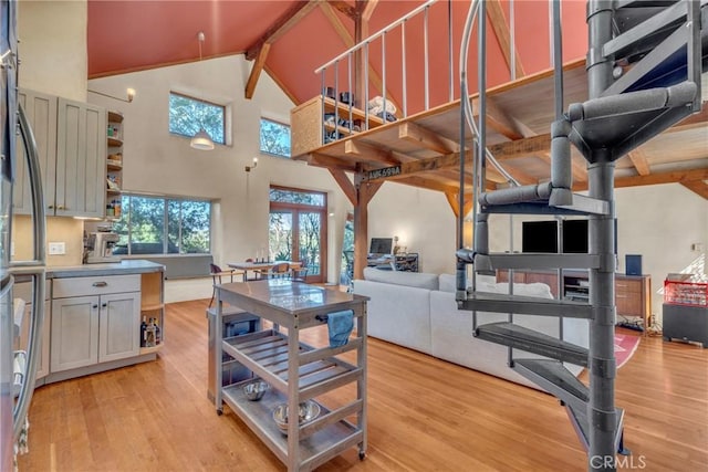 kitchen featuring beam ceiling, high vaulted ceiling, open shelves, open floor plan, and light wood-style floors