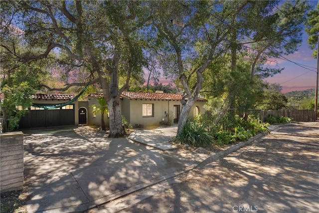 view of front of property with a tile roof, fence, and stucco siding