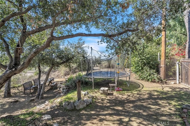 view of yard featuring a trampoline and fence