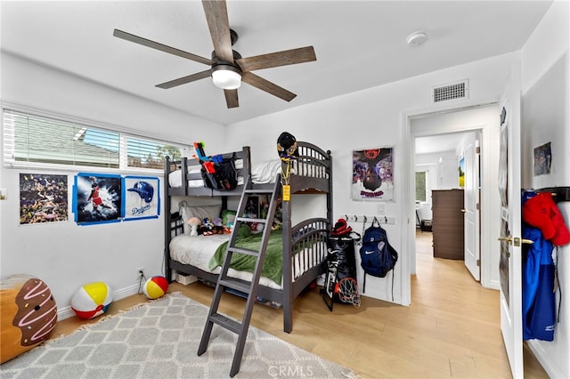 bedroom featuring baseboards, wood finished floors, visible vents, and ceiling fan