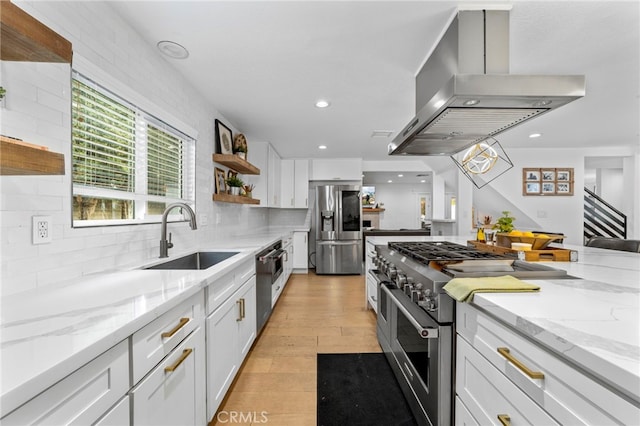 kitchen featuring island exhaust hood, open shelves, a sink, white cabinetry, and stainless steel appliances