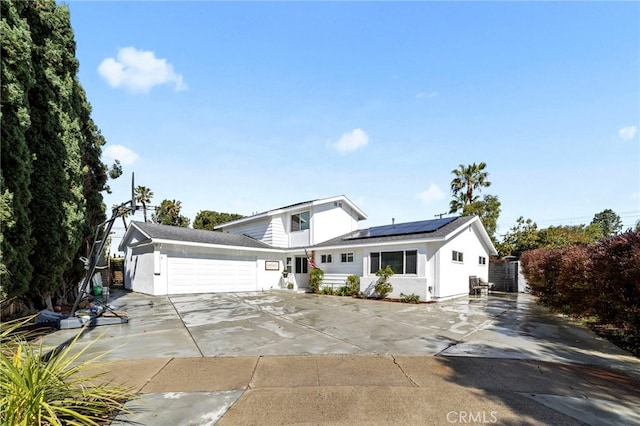 traditional home featuring solar panels, concrete driveway, central AC unit, stucco siding, and a garage