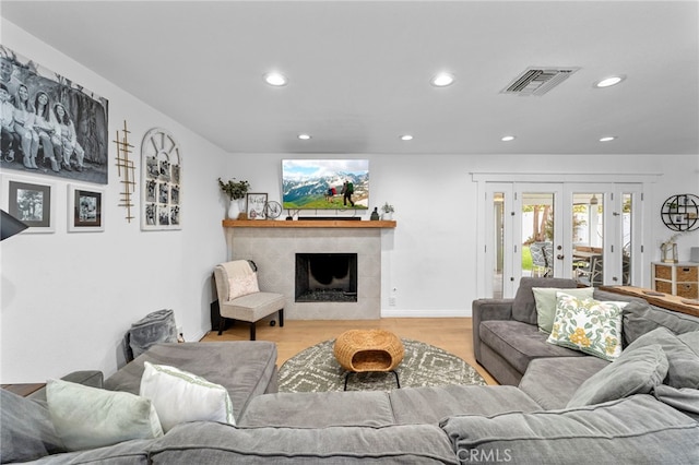 living room with visible vents, light wood-style flooring, a fireplace, recessed lighting, and french doors