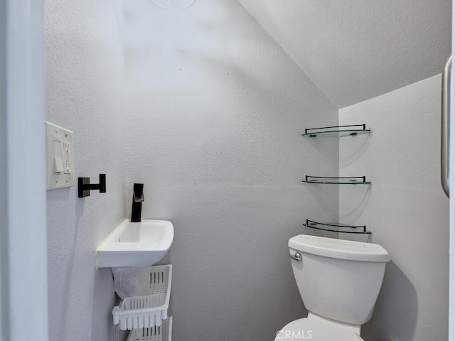 bathroom featuring toilet and a textured wall