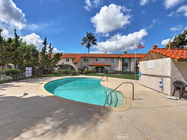 pool with a patio area and fence