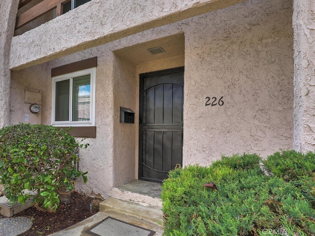 doorway to property featuring stucco siding