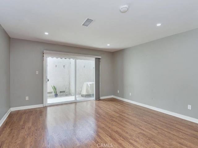 empty room featuring recessed lighting, wood finished floors, visible vents, and baseboards