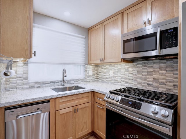 kitchen featuring light brown cabinets, a sink, backsplash, stainless steel appliances, and light stone countertops