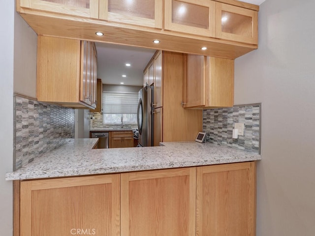 kitchen featuring decorative backsplash, glass insert cabinets, appliances with stainless steel finishes, and a sink