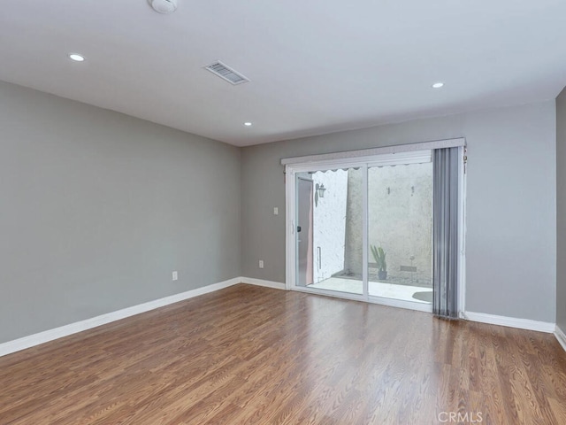 empty room with visible vents, recessed lighting, baseboards, and wood finished floors