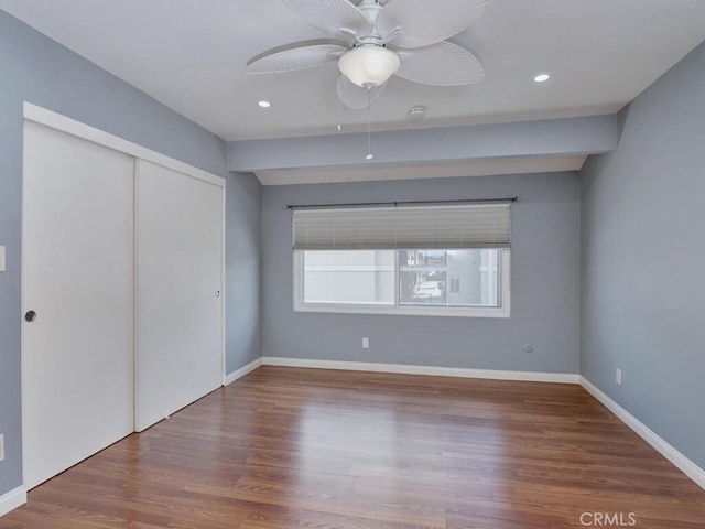 unfurnished bedroom with recessed lighting, wood finished floors, a closet, and baseboards