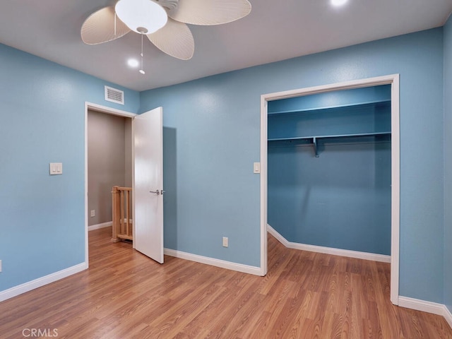 unfurnished bedroom with a closet, visible vents, baseboards, and wood finished floors