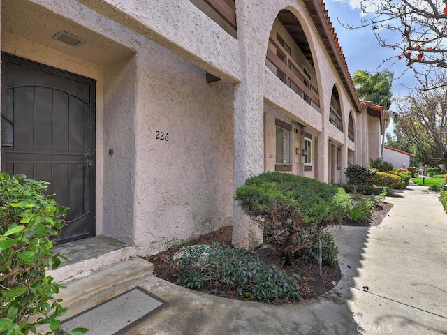 doorway to property featuring stucco siding and visible vents