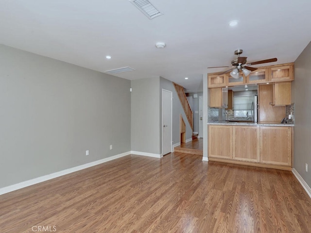 kitchen featuring a ceiling fan, wood finished floors, light countertops, decorative backsplash, and baseboards