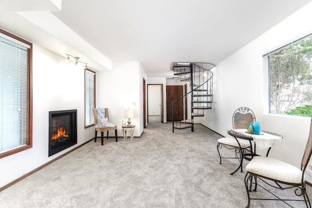 sitting room featuring stairway, carpet flooring, a wealth of natural light, and a lit fireplace