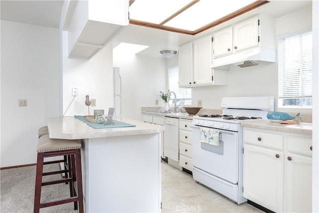 kitchen with under cabinet range hood, a sink, white appliances, white cabinets, and light countertops