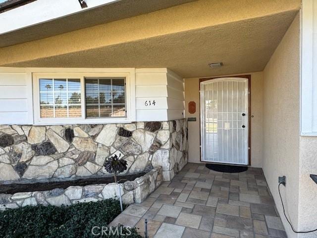 doorway to property featuring stone siding and stucco siding