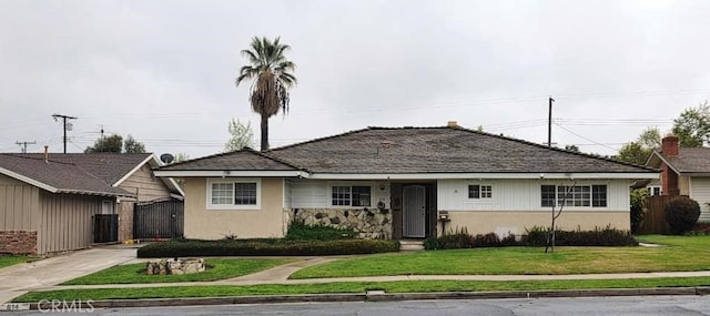 view of front of property with stucco siding, a front lawn, a gate, fence, and concrete driveway