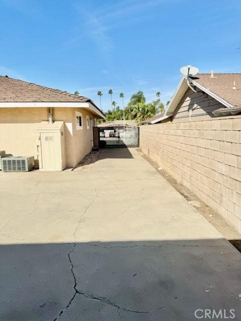 view of side of property featuring a gate, stucco siding, driveway, and fence