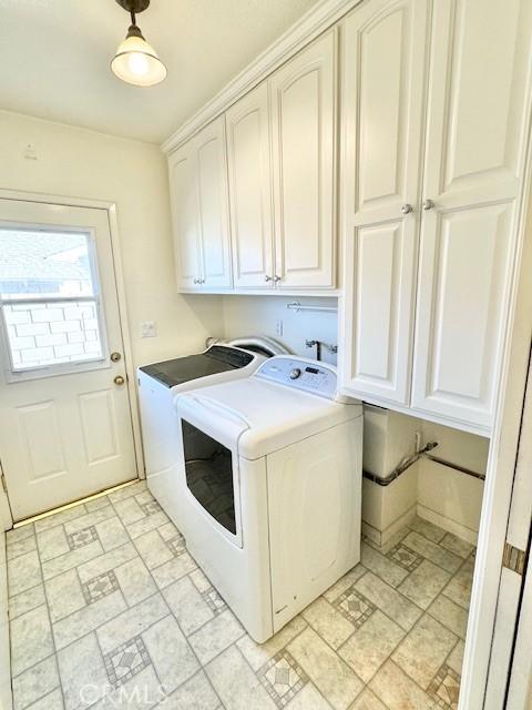 laundry area with stone finish floor, cabinet space, and washing machine and clothes dryer