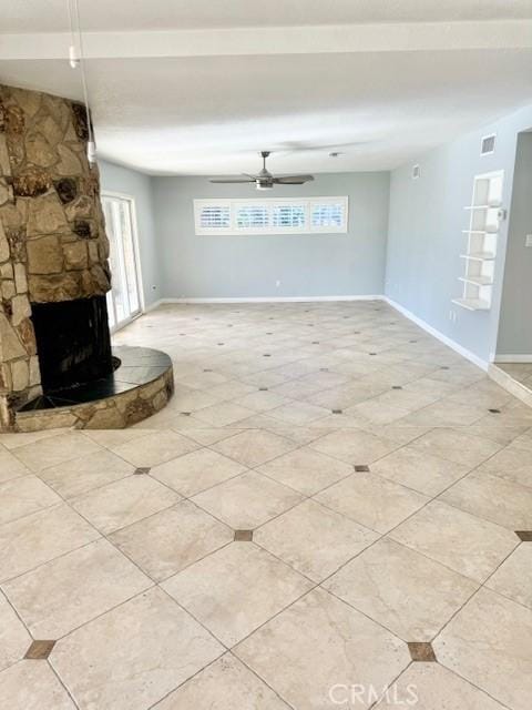 unfurnished living room featuring a stone fireplace, visible vents, baseboards, and a healthy amount of sunlight