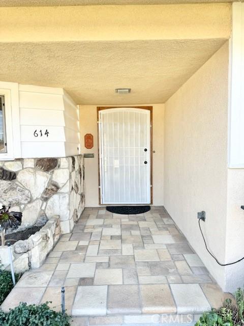 view of exterior entry with visible vents and stucco siding