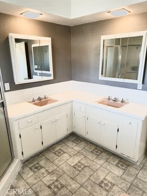 bathroom featuring vanity, a shower with shower door, and visible vents