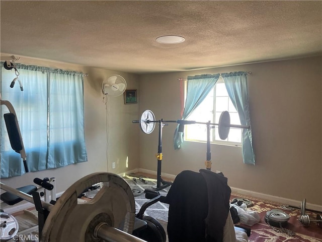 exercise room featuring baseboards and a textured ceiling