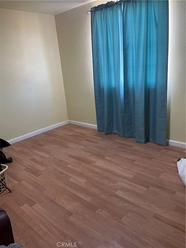 spare room with baseboards and wood finished floors