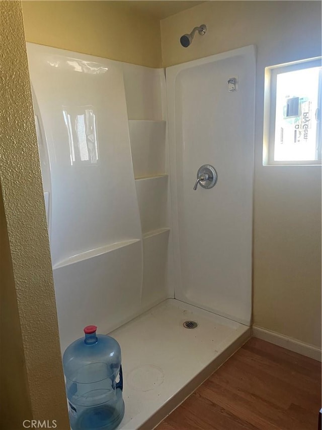 full bath featuring baseboards, wood finished floors, and a shower stall