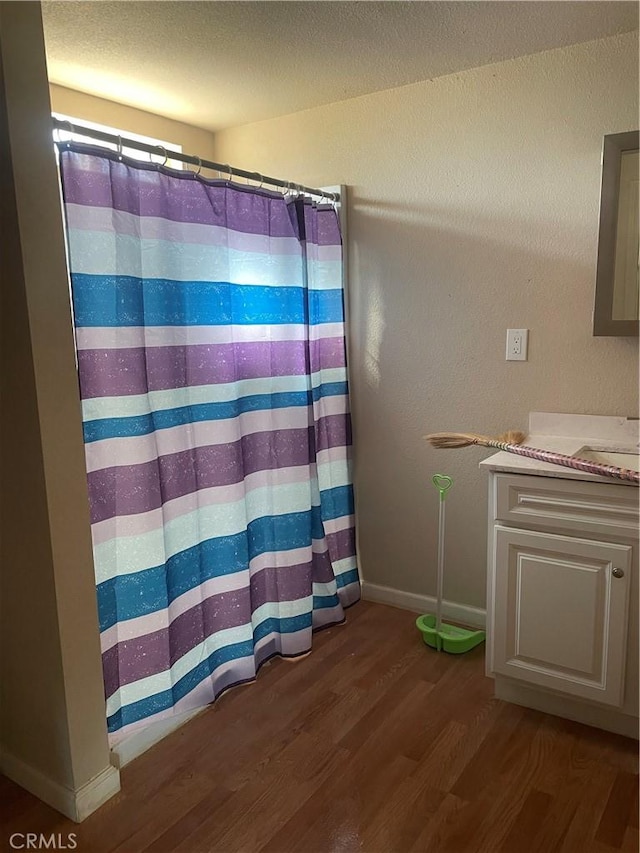 bathroom featuring vanity, a shower with curtain, wood finished floors, baseboards, and a textured ceiling