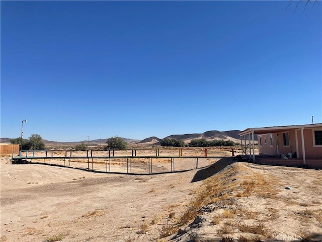 view of yard featuring a rural view, a mountain view, and fence