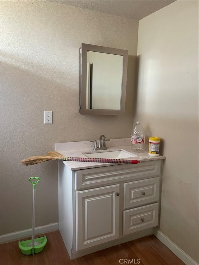 bathroom with baseboards, wood finished floors, and vanity