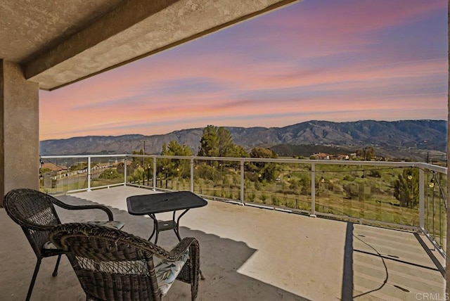 balcony at dusk featuring a mountain view