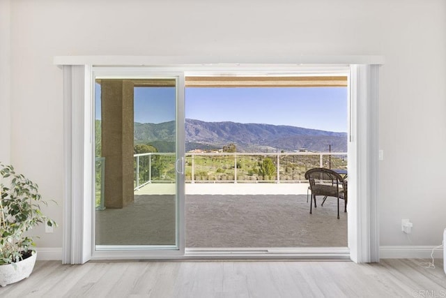 doorway to outside featuring a mountain view, wood finished floors, and baseboards