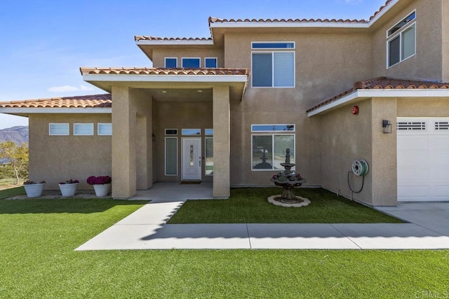 back of property with a garage, stucco siding, a tile roof, and a lawn