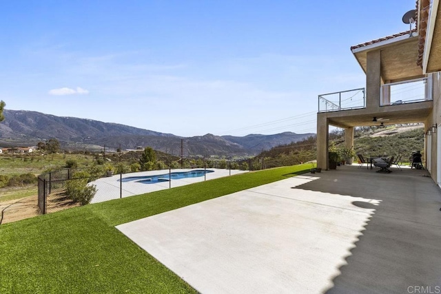 view of patio / terrace with an outdoor pool, a mountain view, and a balcony