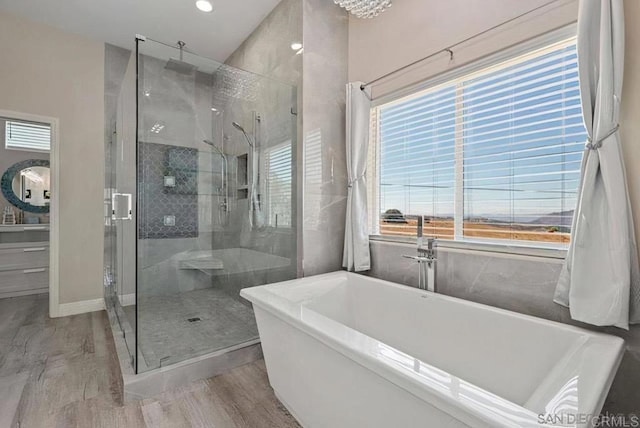 full bath with a stall shower, a freestanding bath, and wood finished floors