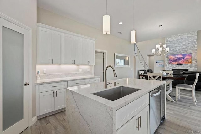 kitchen with light wood finished floors, light stone counters, a chandelier, and a sink