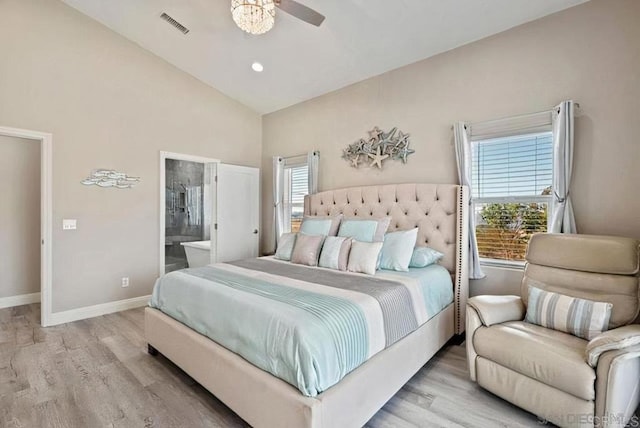 bedroom featuring visible vents, baseboards, vaulted ceiling, wood finished floors, and ensuite bath