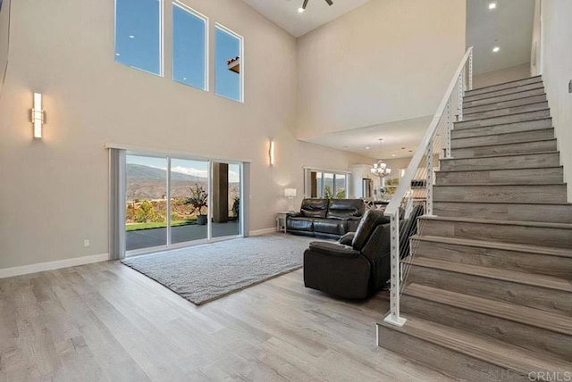 living area featuring a healthy amount of sunlight, stairs, an inviting chandelier, and wood finished floors