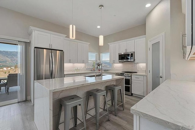 kitchen with a sink, a kitchen bar, appliances with stainless steel finishes, and white cabinetry