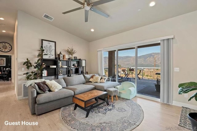 living area with visible vents, ceiling fan, vaulted ceiling, light wood-style floors, and a mountain view