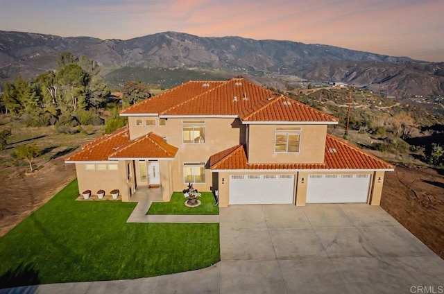 mediterranean / spanish home with stucco siding, a tile roof, a mountain view, concrete driveway, and an attached garage