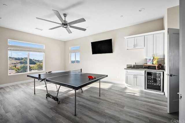 playroom with a ceiling fan, wood finished floors, beverage cooler, and baseboards