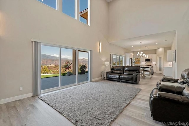 living area with baseboards, an inviting chandelier, and light wood-style flooring