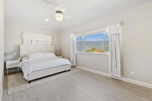 bedroom with visible vents, baseboards, and wood finished floors