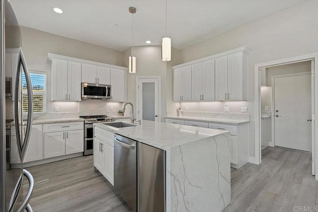 kitchen with a sink, appliances with stainless steel finishes, light wood-style flooring, and white cabinets